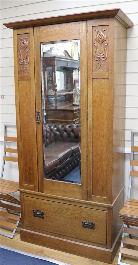 An Edwardian Art Nouveau oak single wardrobe, with mirrored door, flanked by stylised tulip head pilasters W.98cm